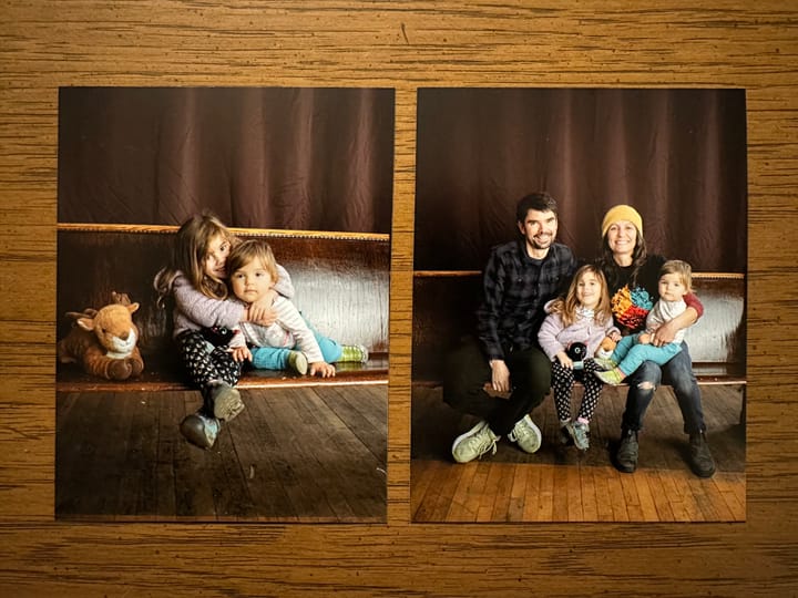 Two photo prints of family portraits on a wood table.